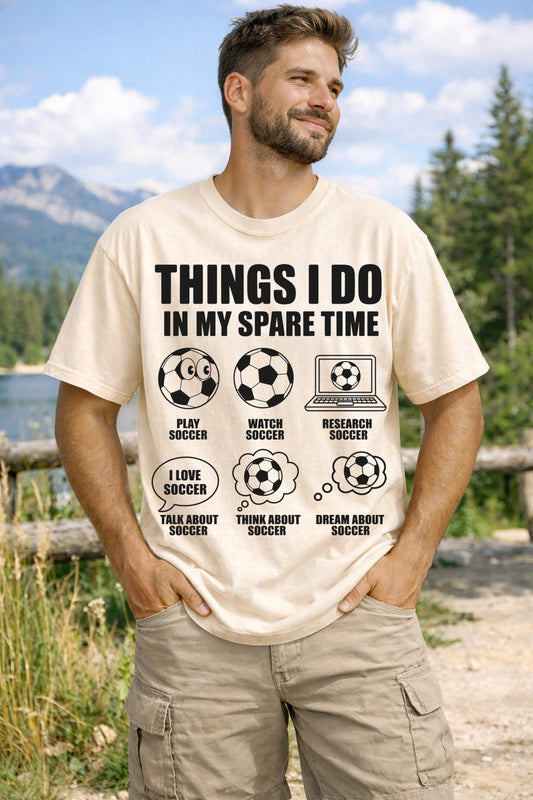 Man wearing a t-shirt with soccer-themed text and graphics in a natural setting.