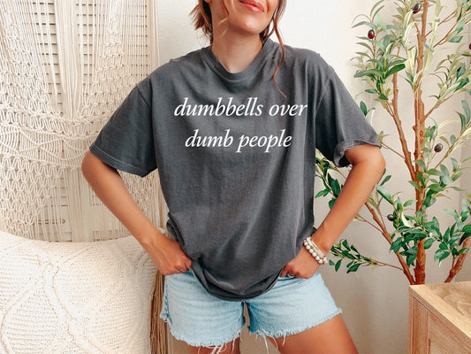 Person wearing a gray t-shirt with text and denim shorts in a casual setting.