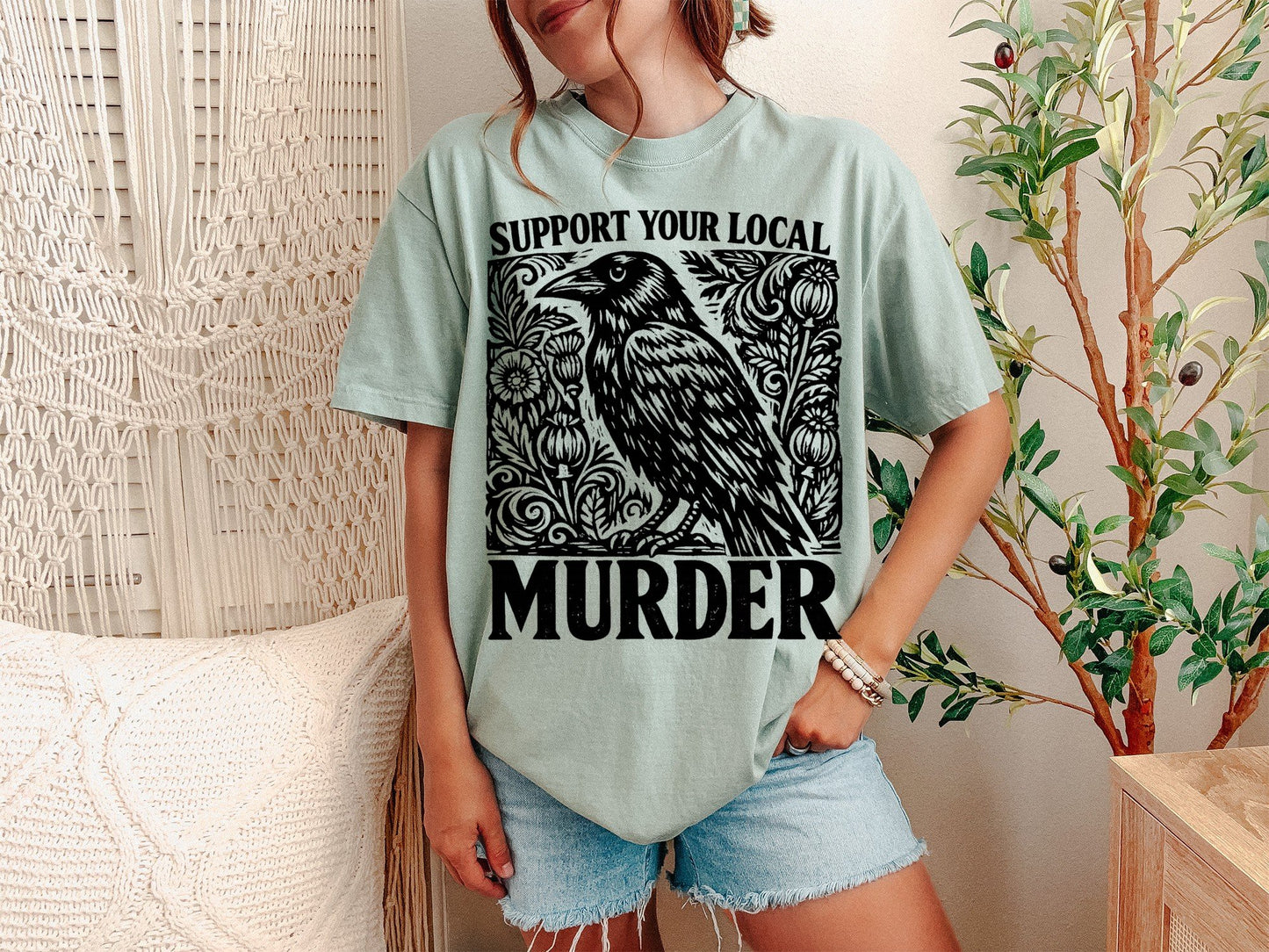 A Bay Unisex Garment-Dyed T-shirt mockup (front view) showing the support your local murder crow shirt - funny bird lover gift tee print on the front. The artwork highlights nature lover gift, crows before bros, support your local murder crow shirt - funny bird lover gift tee, unisex garment-dyed t-shirt, bay, support, your, local, murder, crow, describing the graphic and theme on the garment.