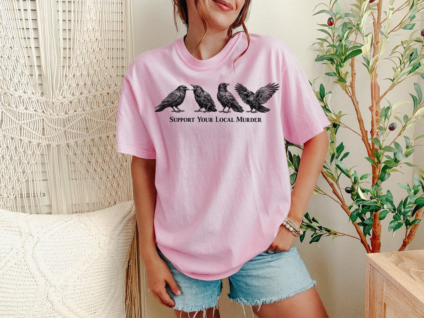 A Blossom Unisex Garment-Dyed T-shirt mockup (front view) showing the support your local murder crow shirt - funny bird lover gift - dark academia raven tee print on the front. The artwork highlights local, murder, crow, shirt, -, funny, bird, lover, gift, dark, describing the graphic and theme on the garment.