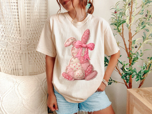 A Ivory Unisex Garment-Dyed T-shirt mockup (front view) showing the pink patchwork bunny coquette shirt - vintage easter bunny bow tee print on the front. The artwork highlights easter bunny shirt, coquette aesthetic, bunny with bow, vintage bunny tee, pink coquette shirt, patchwork rabbit, shabby chic bunny, balletcore bunny, soft girl aesthetic, easter gift for her, describing the graphic and theme on the garment.