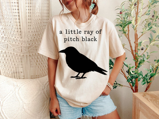 A Ivory Unisex Garment-Dyed T-shirt mockup (front view) showing the a little ray of pitch black shirt - goth aesthetic sarcastic tee print on the front. The artwork highlights sarcastic shirt, pitch black, emo aesthetic, spooky season, minimalist goth, alt fashion, funny gift for her, comfort colors, graphic tee, sad girl aesthetic, describing the graphic and theme on the garment.