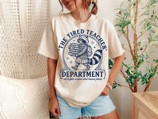 A Ivory Unisex Garment-Dyed T-shirt mockup (front view) showing the the tired teachers department shirt - funny swiftie teacher gift - back to school tee print on the front. The artwork highlights tired teacher, ttpd parody, teacher gift, back to school, teacher era, comfort colors, funny teacher tee, elementary teacher, teacher appreciation, tortured teacher, describing the graphic and theme on the garment.