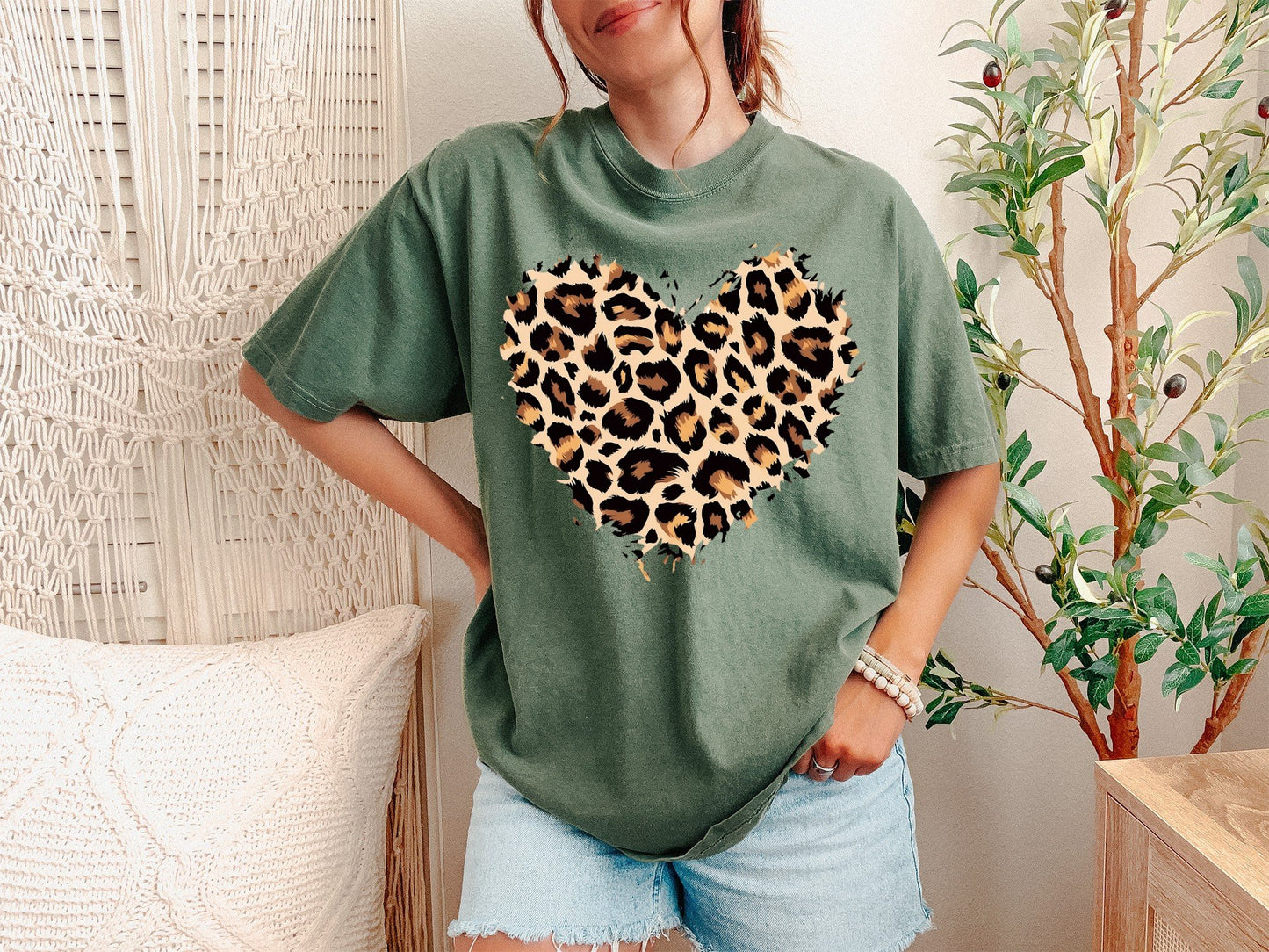 A Moss Unisex Garment-Dyed T-shirt mockup (front view) showing the leopard heart shirt - cute valentines day animal print tee print on the front. The artwork highlights valentines gift for her, cute animal print, cheetah print top, wild heart tee, leopard heart gift, trendy graphic tee, womens fashion 2025, boho style shirt, leopard heart design, heart pattern tee, describing the graphic and theme on the garment.
