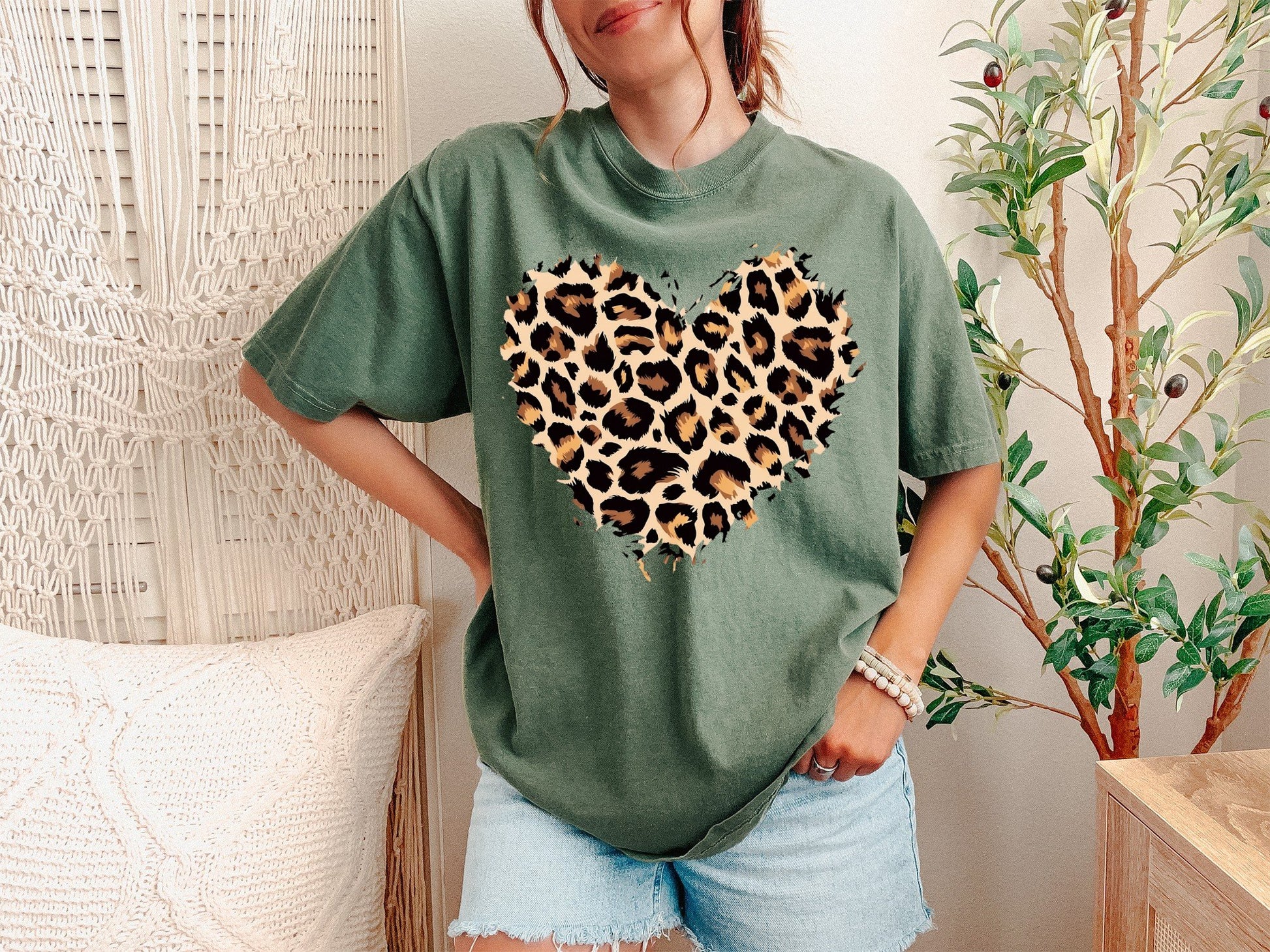 A Moss Unisex Garment-Dyed T-shirt mockup (front view) showing the leopard heart shirt - cute valentines day animal print tee print on the front. The artwork highlights valentines gift for her, cute animal print, cheetah print top, wild heart tee, leopard heart gift, trendy graphic tee, womens fashion 2025, boho style shirt, leopard heart design, heart pattern tee, describing the graphic and theme on the garment.