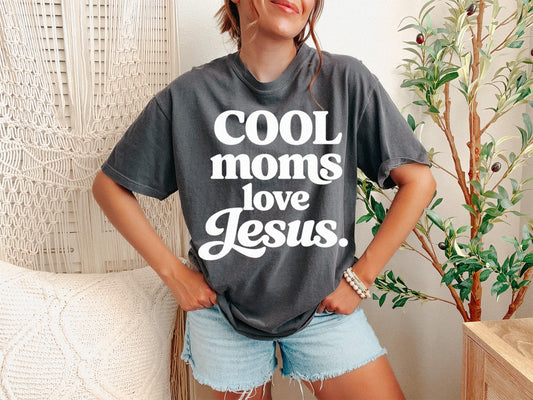 A Pepper Unisex Garment-Dyed T-shirt mockup (front view) showing the retro cool moms love jesus shirt - vintage christian mama tee - aesthetic faith based gift print on the front. The artwork highlights cool mom shirt, faith based gift, retro mama tee, comfort colors, religious shirt, mothers day gift, wavy text shirt, aesthetic christian, blessed mama, praying mama, describing the graphic and theme on the garment.