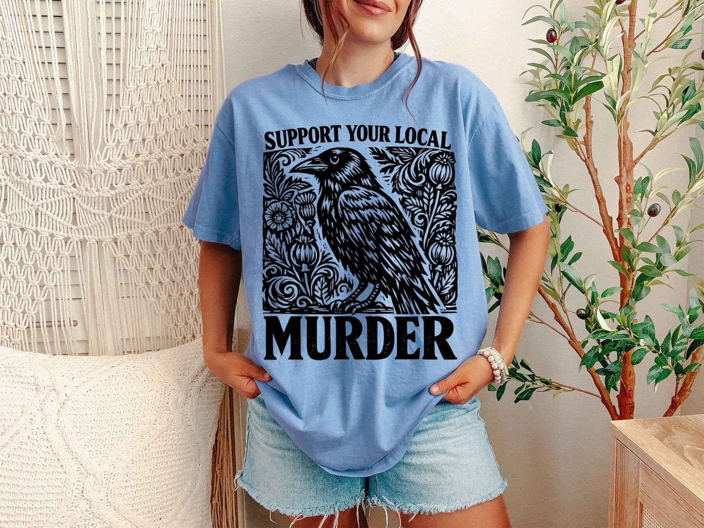 A Washed Denim Unisex Garment-Dyed T-shirt mockup (front view) showing the support your local murder crow shirt - funny bird lover gift tee print on the front. The artwork highlights t-shirt, crow shirt, murder of crows, support local murder, bird lover gift, crowcore aesthetic, goblincore shirt, funny bird pun, dark academia shirt, witchy crow tee, describing the graphic and theme on the garment.